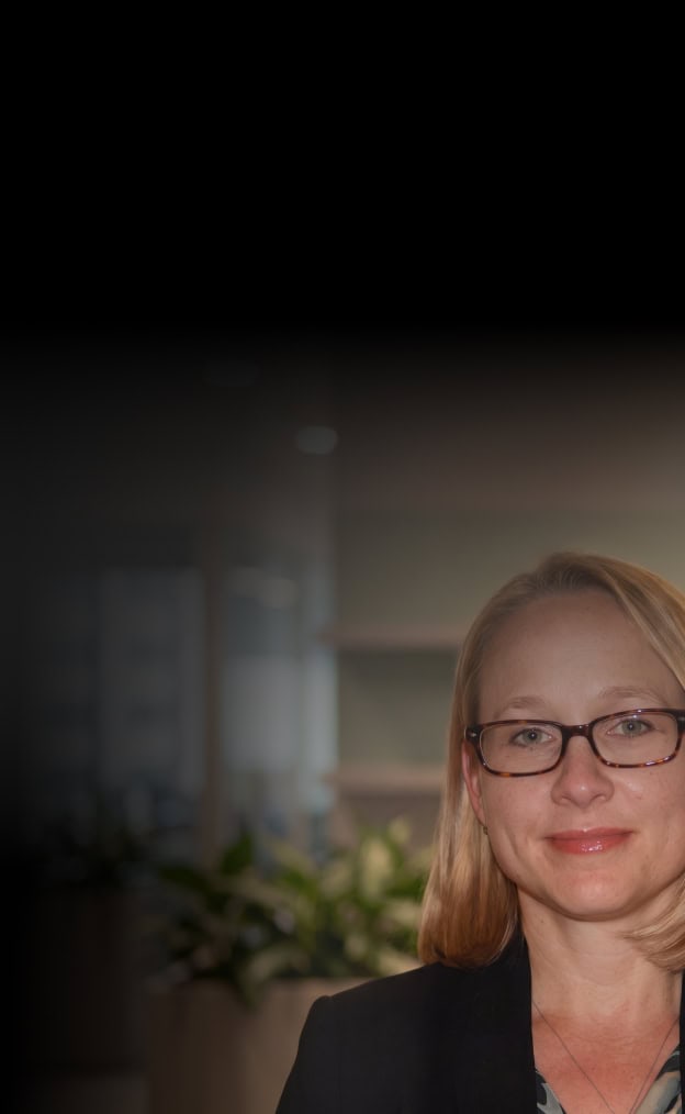 Businesswoman with glasses in an office setting, representing Maxio's innovative solutions.