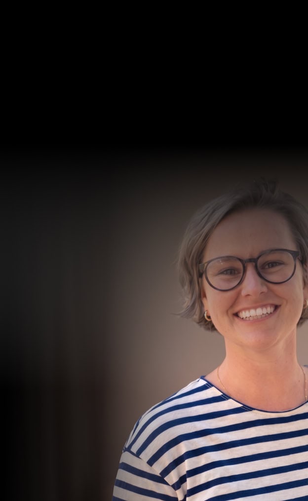 Smiling woman with glasses in a professional setting.