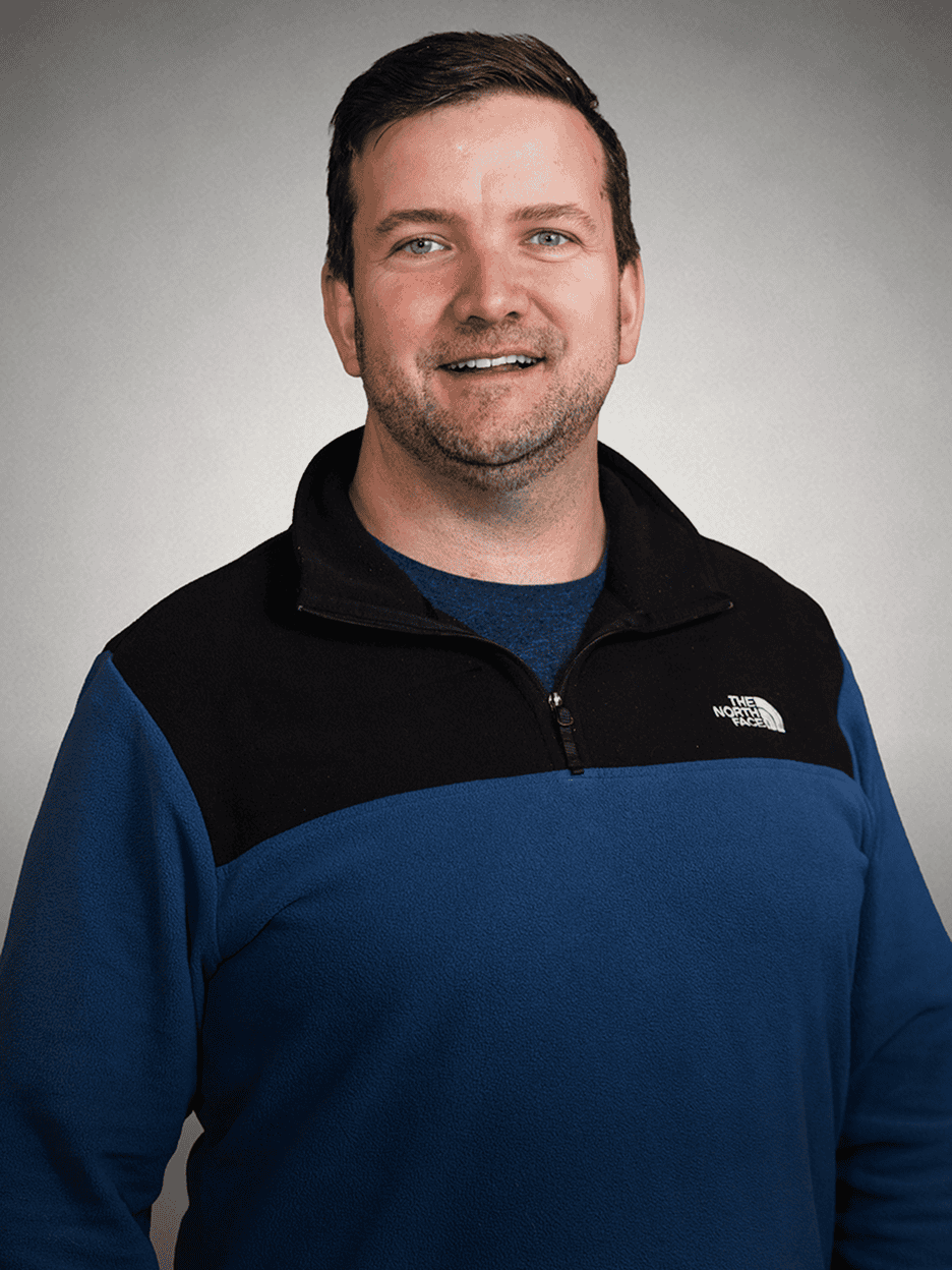 Smiling man in blue and black North Face jacket for Maxio.