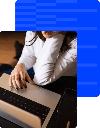 Businesswoman working on a laptop with a smartphone nearby, focused on her task.