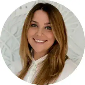 Smiling woman with long brown hair in a white blouse, professional portrait.